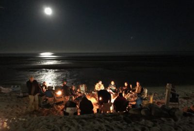 Group of Escapees around a campfire on the beach
