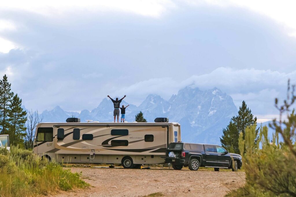 Father and son stand on RV facing mountains