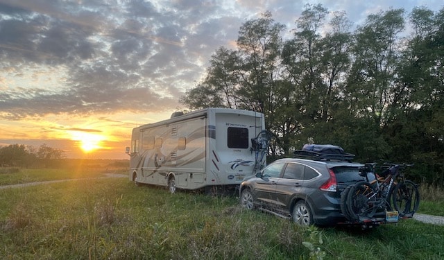 RV towing car into sunset