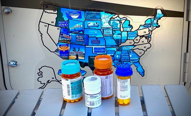Prescription bottles in front of a travel map, positioned in front of an RV