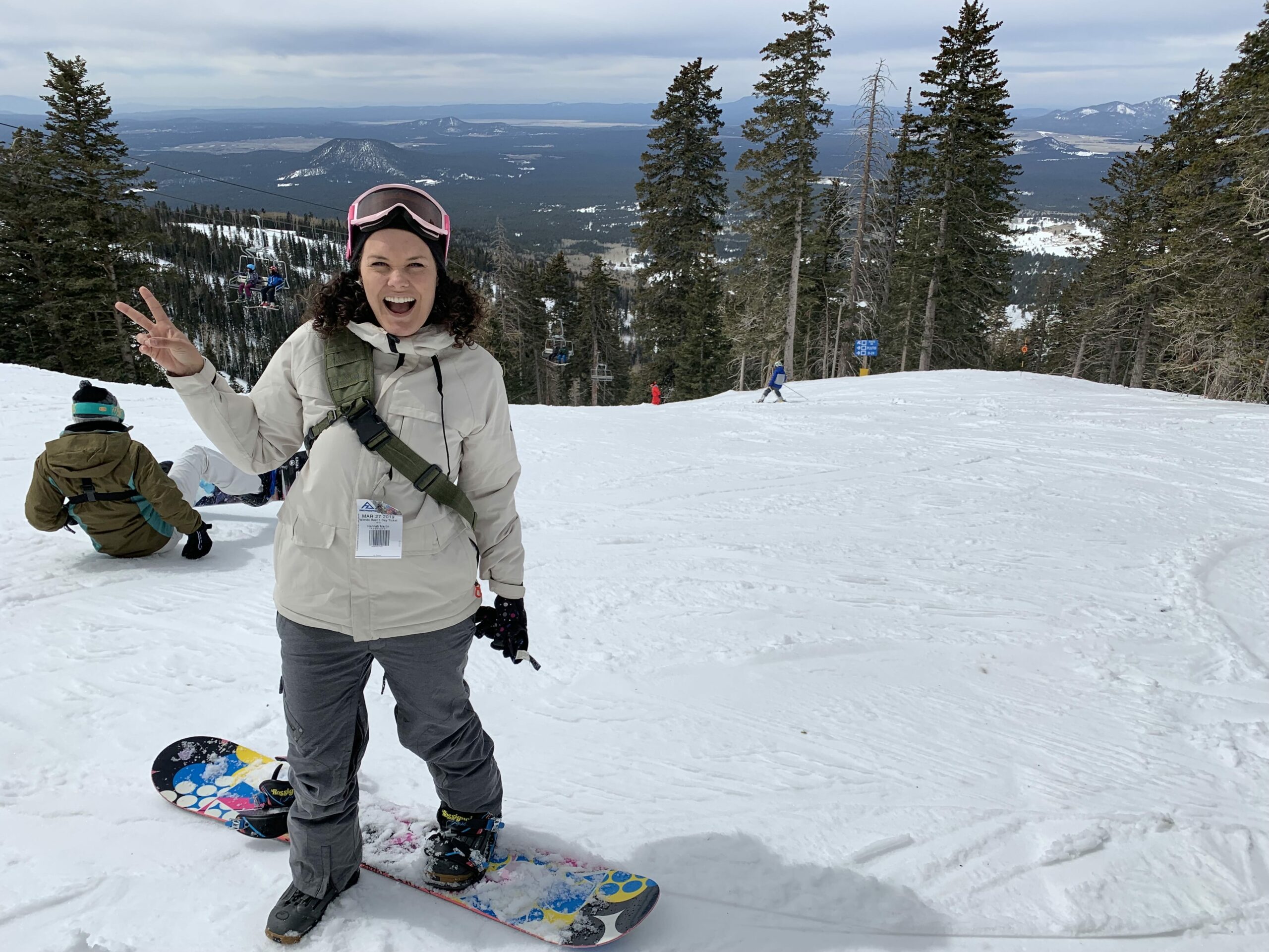 woman standing on snowboard on side of snowy mountain
