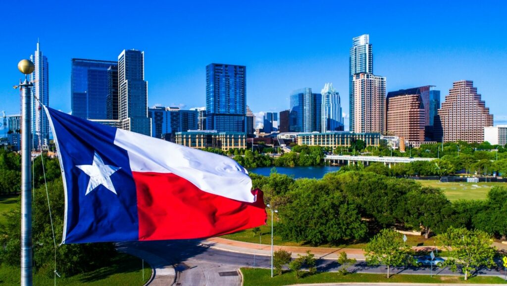 Texas flag in foreground of view of Austin Texas skyline